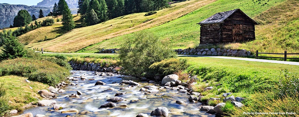 Livigno: fiume circondato da un prato verde e una casetta in legno