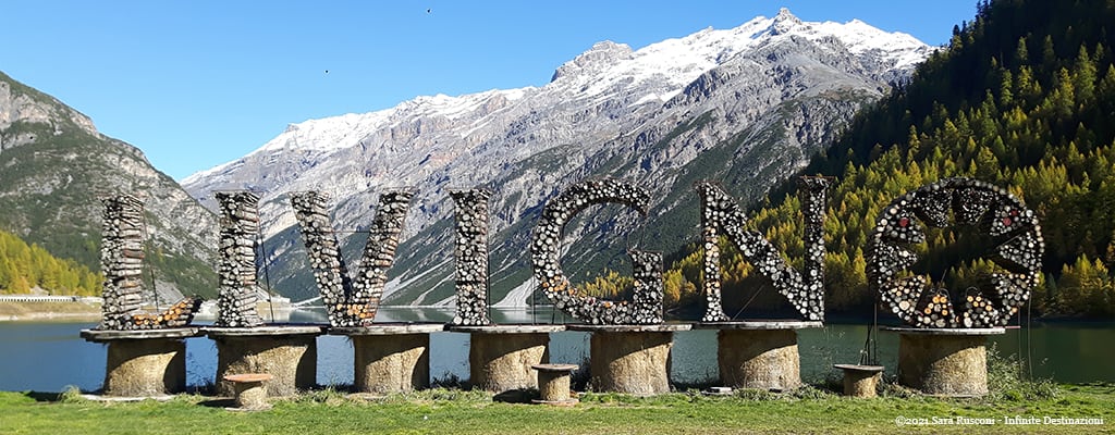 Lago di Livigno con la scritta "Livigno" realizzata con tronchi di legno