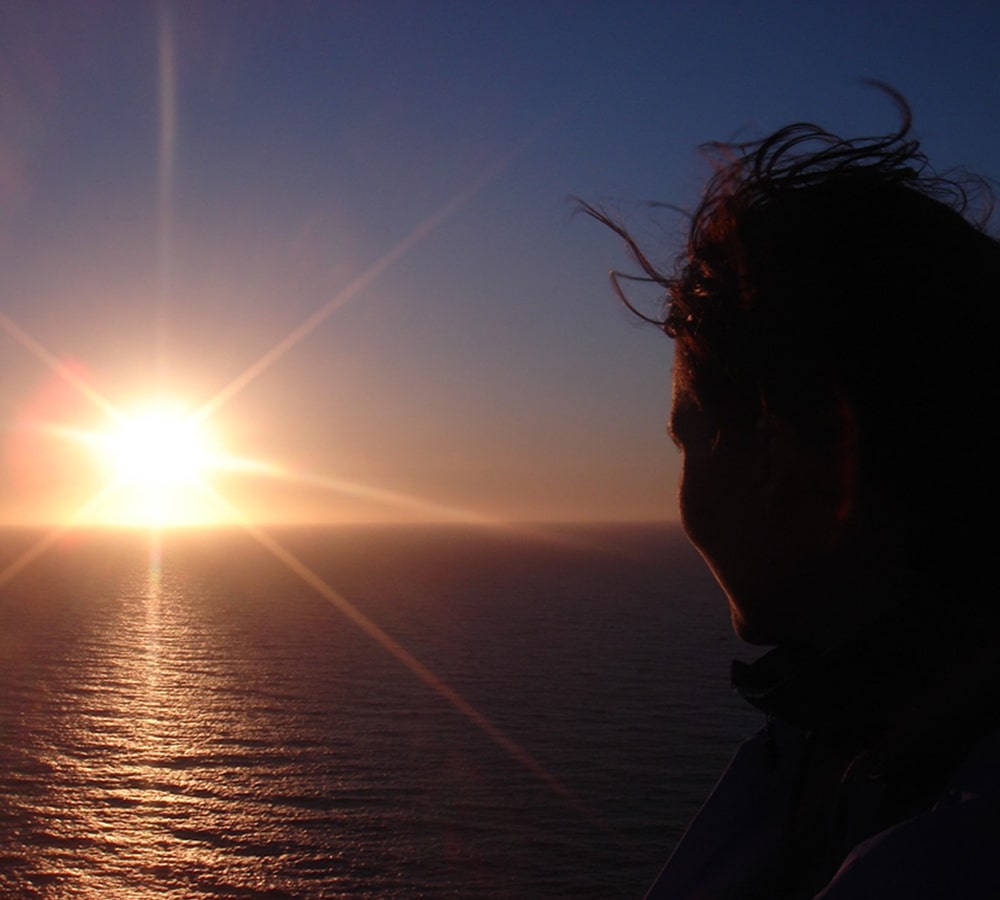Ragazza che guarda il tramonto sull'oceano